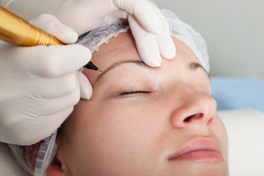 Cosmetologist making permanent makeup on eye brows