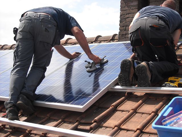 Two workers installing commercial solar panels